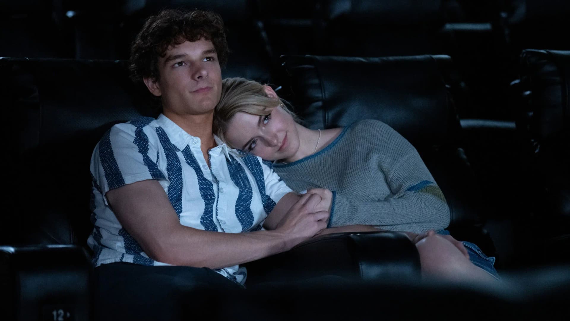 Mason Thames and Mckenna Grace sharing an intimate moment together in a cinema during a scene from Regretting You