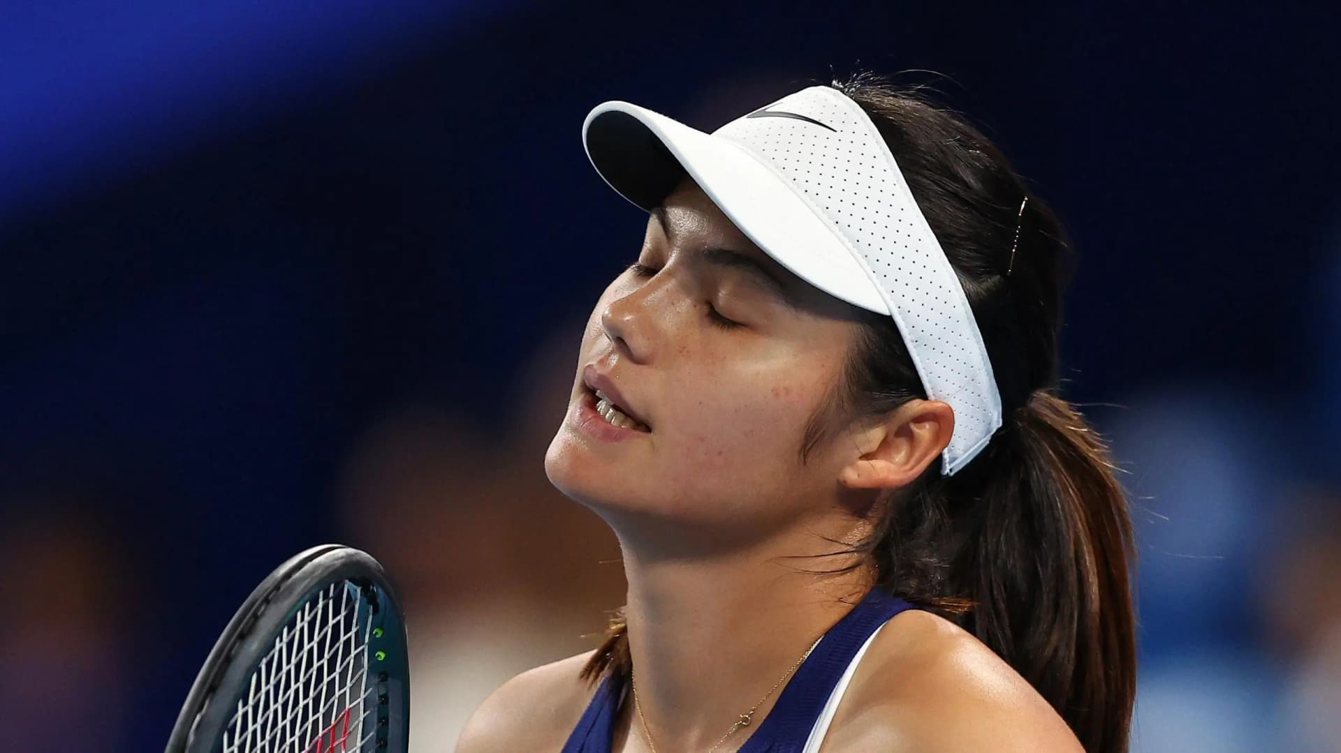 Emma Raducanu stands on court with a concerned expression, referencing her foot injury that kept her out of Great Britain's opening United Cup match